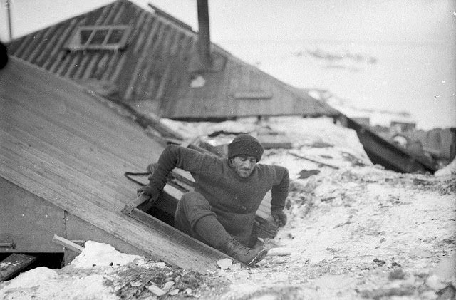 #22 Mertz leaving the hut by the trapdoor on the verandah roof, 1912