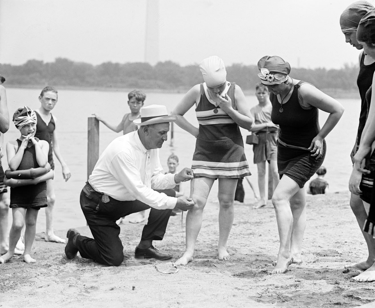 #20 Woman having her swimsuit measured for length violations on a Washington DC beach, 1922