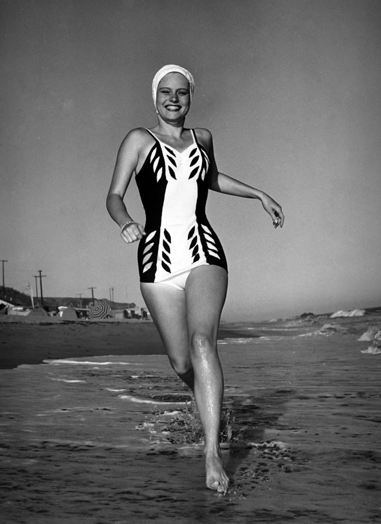 #39 Actress Alexis Smith in a swimming costume running along the beach in southern California, 1940