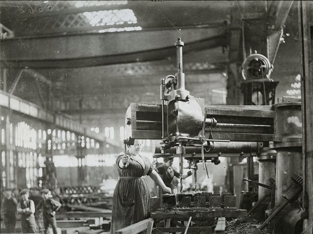 Woman at battery drills, drilling angles and T bars for ribs of airship sheds