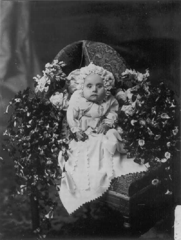 Deceased baby whose eyes are likely painted open.