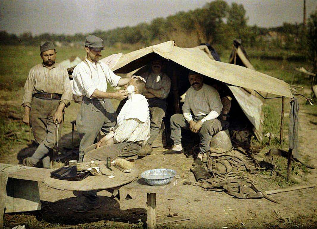 Two French soldiers heat up a meal on an outdoor fireplace made from brick, 1917.