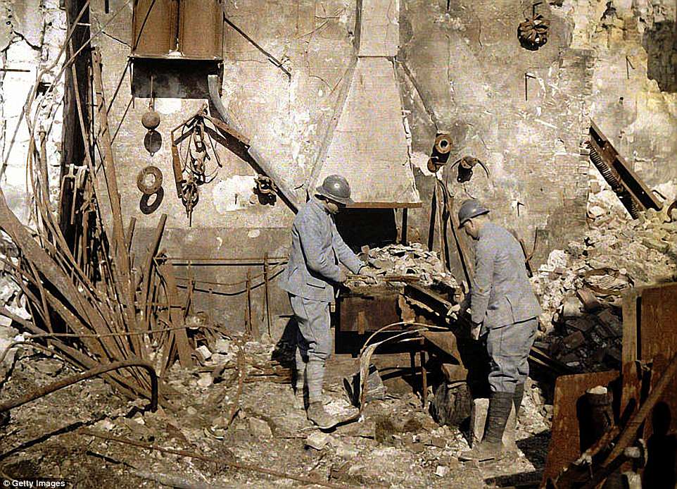 Two French soldiers working at the smith’s hearth in a forge destroyed by grenades, in Reims, France, 1917