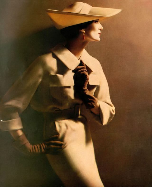 #48 Carmen Dell’ Orefice in beige wool and silk suit with patch pockets set high on the bosom worn with thin straw hat, 1958.