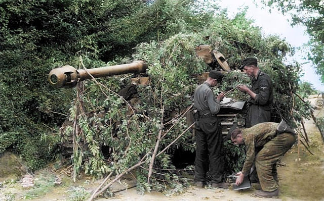#22 German troops camouflage a Panzer VI Tiger tank with undergrowth in the Normandy village of Villers-Bocage.