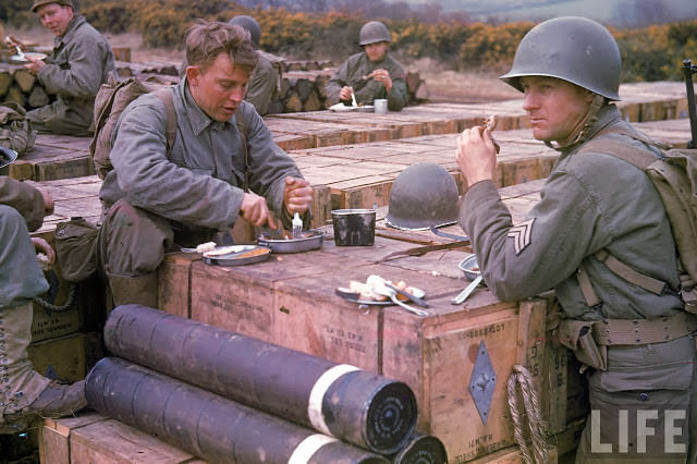 #8 American combat engineer soldiers eating meals atop boxes of ammunition being stockpiled for the impending D-Day invasion of France.