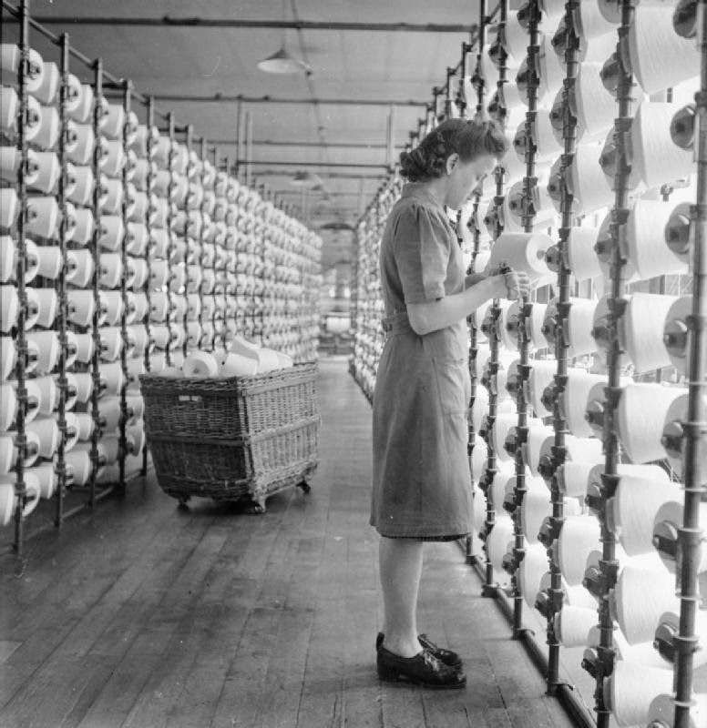 #16 Cotton worker Lilian Alston fits cones of yarn into the V-shaped creel of the warping frame at a cotton mill, somewhere in Lancashire, 1945.