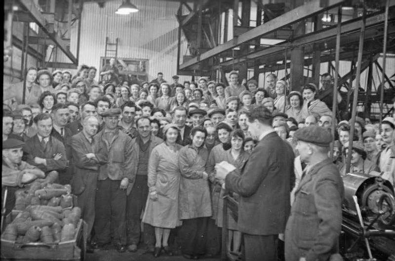 #21 A director, possibly Mr Franklyn Pool, of J & F Pool Ltd reads a telegram from the Ministry of Supply to the workers gathered on the factory floor, congratulating them on the production of their 1 millionth mortar bomb, 1943.
