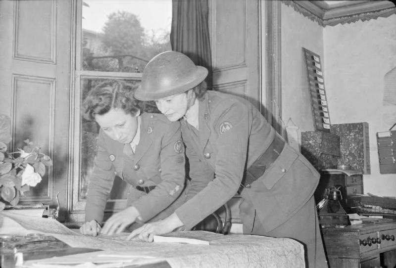 #10 Before they leave the depot to attend an incident, women of the American Ambulance Great Britain look at a map to plan their route. A telephone call has just been received to say that several of their ambulances are needed, 1944.