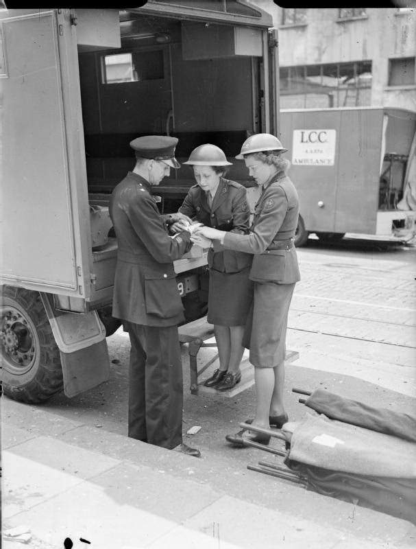#11 A police officer has his hand bandaged by women of the American Ambulance Great Britain following a V1 attack in Upper Norwood. The original caption states that the policeman’s hand was injured by flying glass, 1944.