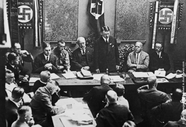 #16 Adolf Hitler (standing, centre) at a party meeting in Munich, 1925