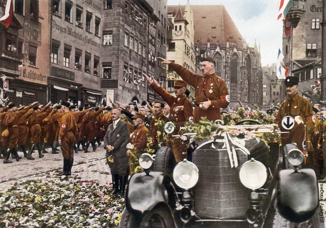 #68 Adolf Hitler, saluting the massed ranks of his party during the party congress at Nuremberg, 1927