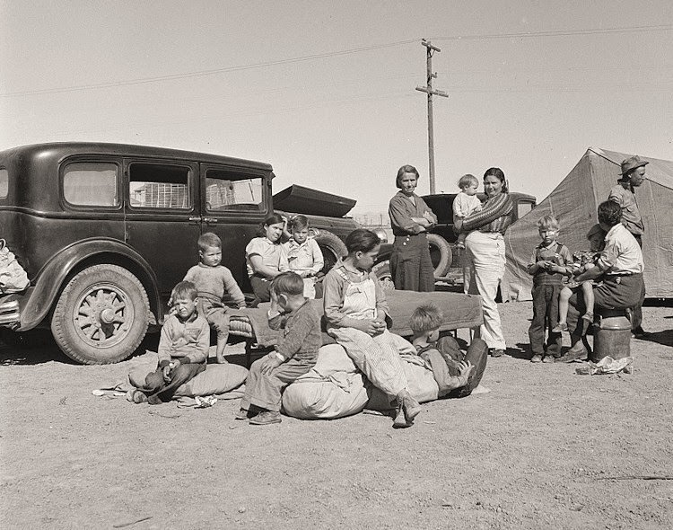 #19 Four families, three of them related with fifteen children, from the Dust Bowl in Texas in an overnight roadside camp near Calipatria, California.