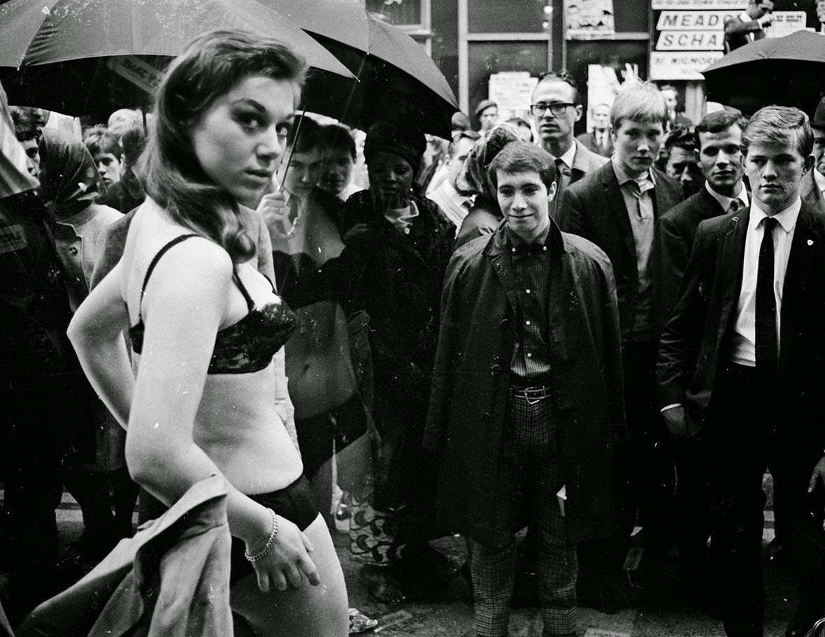 #27 Men watch as a model takes part in a photo shoot in the window of a new Henry Moss boutique on London’s fashionable Carnaby Street, 1966