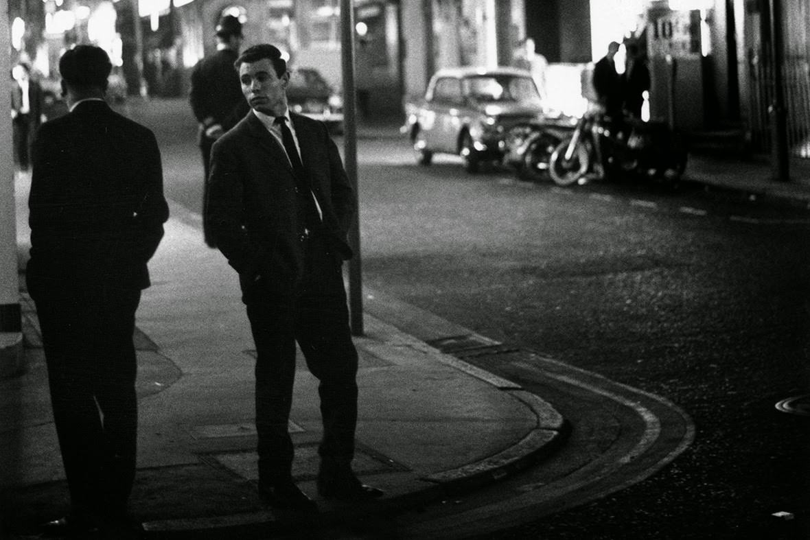 #29 Two men look at each other while standing on a street corner in Soho, 1966
