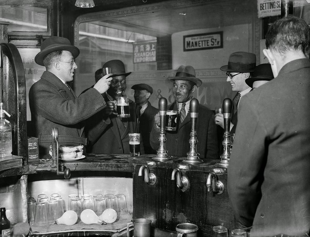 #6 Men raise their glasses in a public house in London’s Soho, 1933