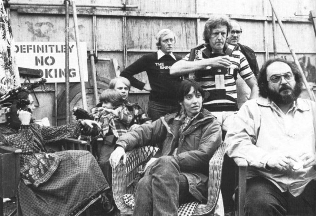 #15 Stanley Kubrick, Shelley Duvall, Danny Lloyd sits in the lap of his on-set coach and longtime Kubrick assistant Leon Vitali. To the left, Kubrick’s daughter Vivian holds the camera she used to film the Making of The Shining documentary. Behind them, Steadicam inventor Garrett Brown stands with camer