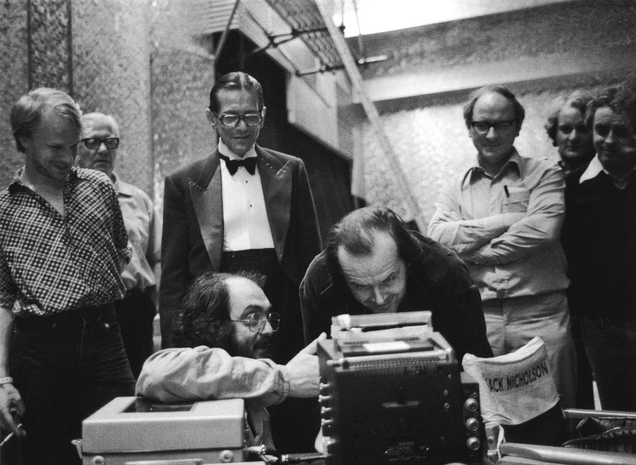 #21 Stanley Kubrick reviews a take with Jack Nicholson on the Gold Room set. Watching from behind are Kubrick assistant Leon Vitali, actor Joe Turkel, Camera Operator Kelvin Pike and Director of Photography John Alcott.