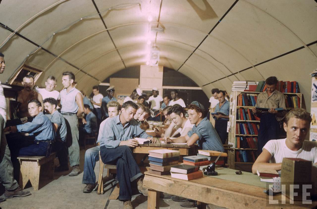 #8 American servicemen relaxing in a quonset hut being used as a library on an island base during WWII.
