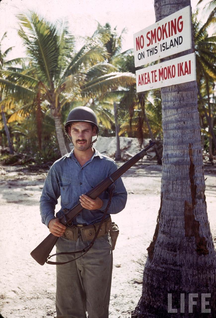 #11 Guard on duty beneath a NO SMOKING sign on Tarawa during WWII.