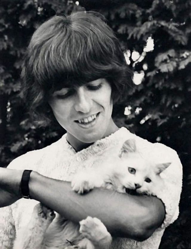 #11 George Harrison with his cat, ‘Corky,’ by the pool at Kinfauns, Surrey, England, 1965.