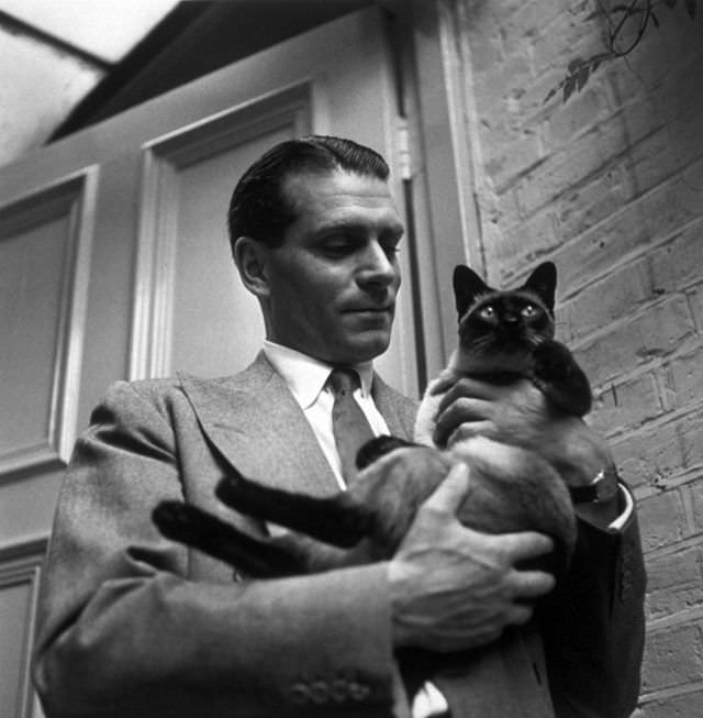 #15 Laurence Olivier with the family cat ‘New’ at home at Chelsea, London, 1946