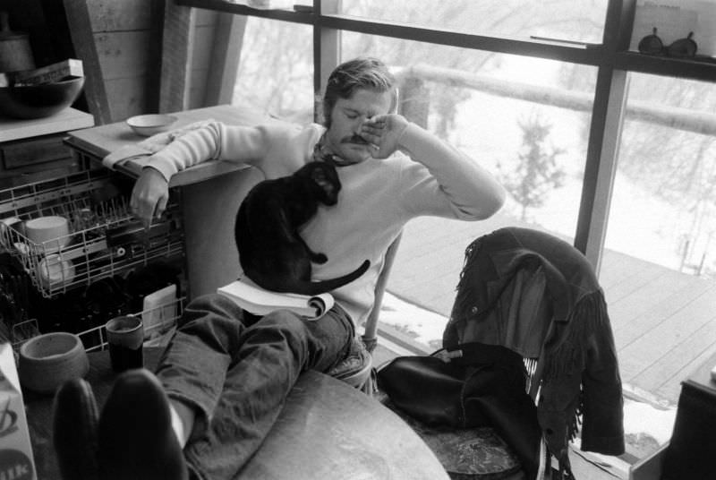 #37 Robert Redford takes a break from reading a script with the family’s cat curled up in his lap at his Utah retreat, 1969