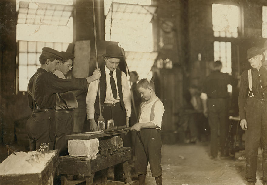 #82 “Teaching the young idea.” The boss (who began at 10 years of age, and has been at it for 30 years) showing a beginner (who is apparently 9 or 10) see 169. Location: Morgantown, west Virginia