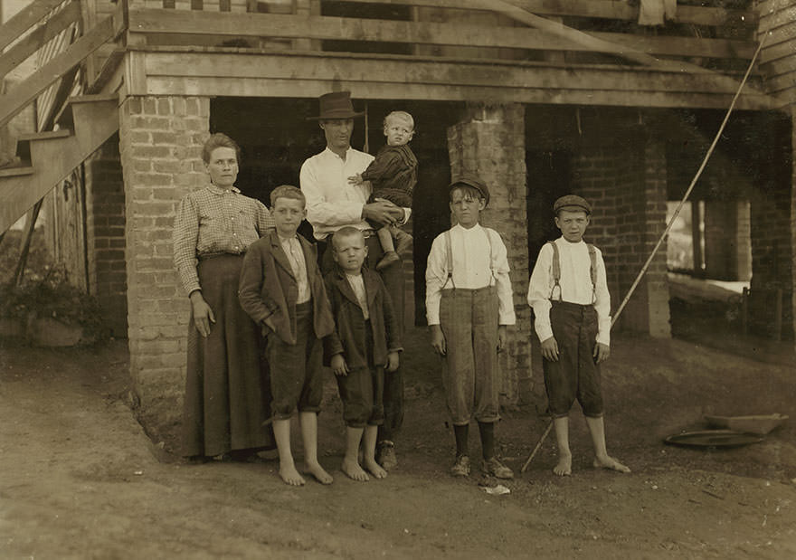 #84 S.D. Ison and family. Father works some. Both boys on right of photo have been in Washington cotton mills, fries, va., for four years. When i asked the smallest worker how old he was, he said, “don’t know,” and looked at his father, who said, “going’ on 14.” Location: fries, Virginia