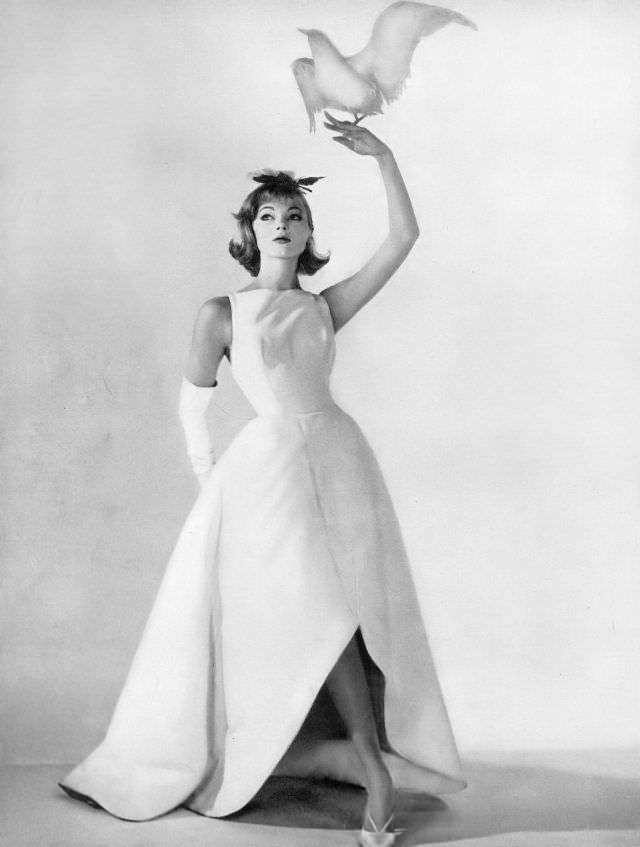 #46 Ivy Nicholson in beautiful evening dress of stiff white cotton ottoman with great petals of skirt that curve up in front and down in back, Harper’s Bazaar, March 1958