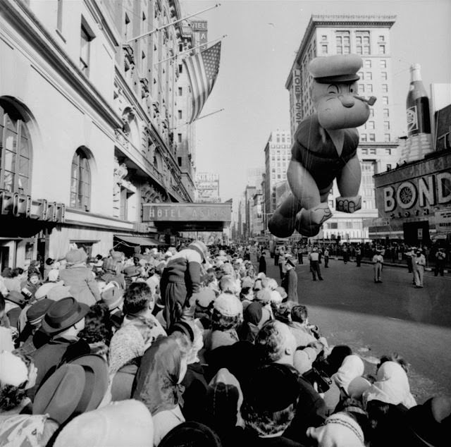 Helium-filled Popeye balloon figure floats above some of the 1,300,000 persons watching the 33rd Macy’s Thanksgiving Day Parade pass through Times Square, New York, November 26, 1959.