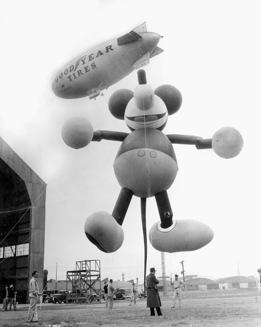 This giant Mickey Mouse balloon, shown tied to dirigible at Glendale in 1934, Calf., was a feature of Macy’s Thanksgiving Day parade, escorting Santa Claus into New York.
