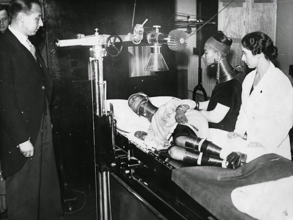 Members of Bertram Mills Freak Show are examined by a medical profession. On the examination table is the ‘Giraffe Necked Woman’, 1935