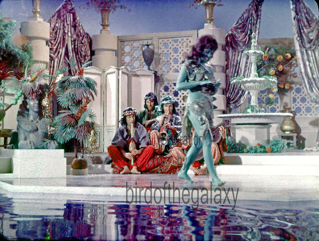 #10 This shot is taken after the scene has finished (maybe it is before the start), as Susan Oliver walks from or towards her mark and stares down at her nails smiling (red lips show up well contrasted to her green face).