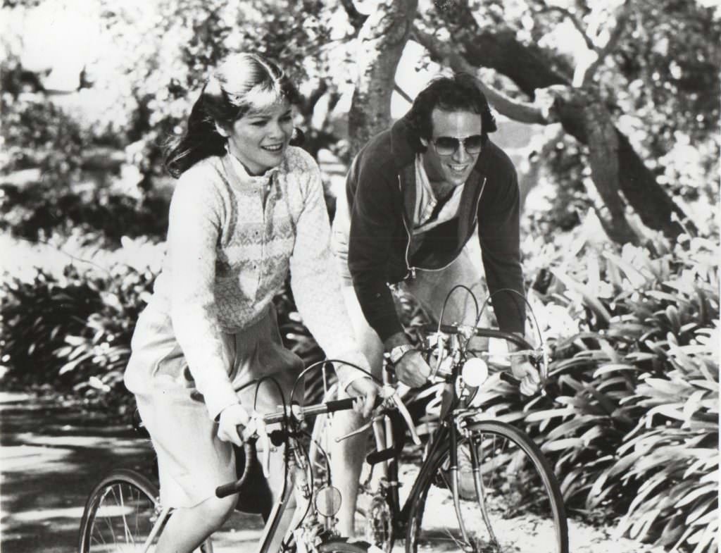 #12 Joan Blondell and Dick Powell riding bikes.