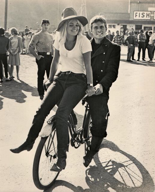 #34 John Phillip Law and Andrea Dromm ride a bike.