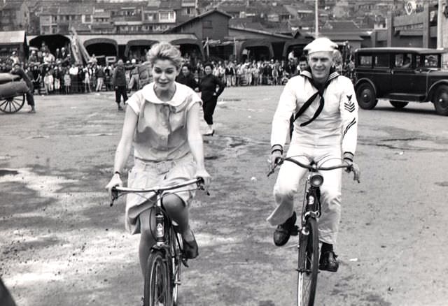 #42 Candice Bergen and Steve McQueen riding bikes.
