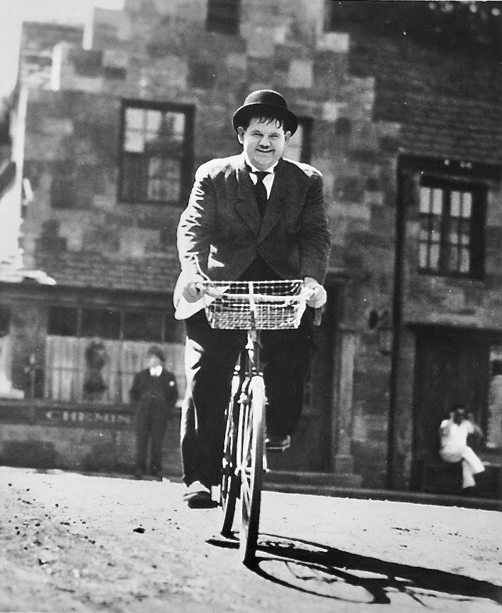 #2 Oliver Hardy riding a bike.