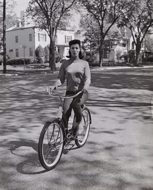 #26 Rita Gam riding a bike.