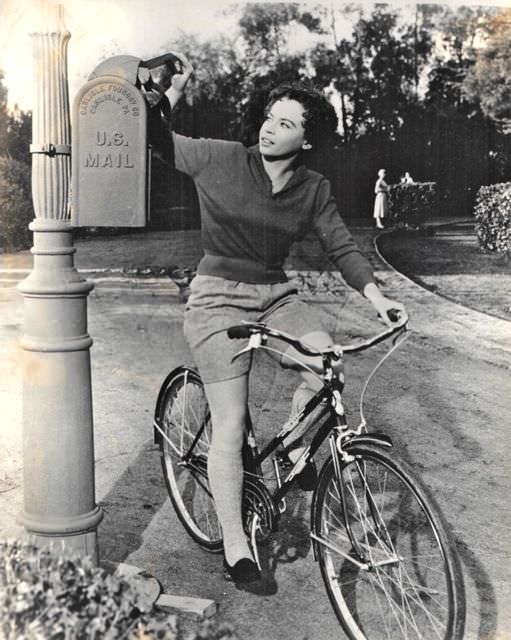 #47 Leslie Caron riding a bike, mails a letter