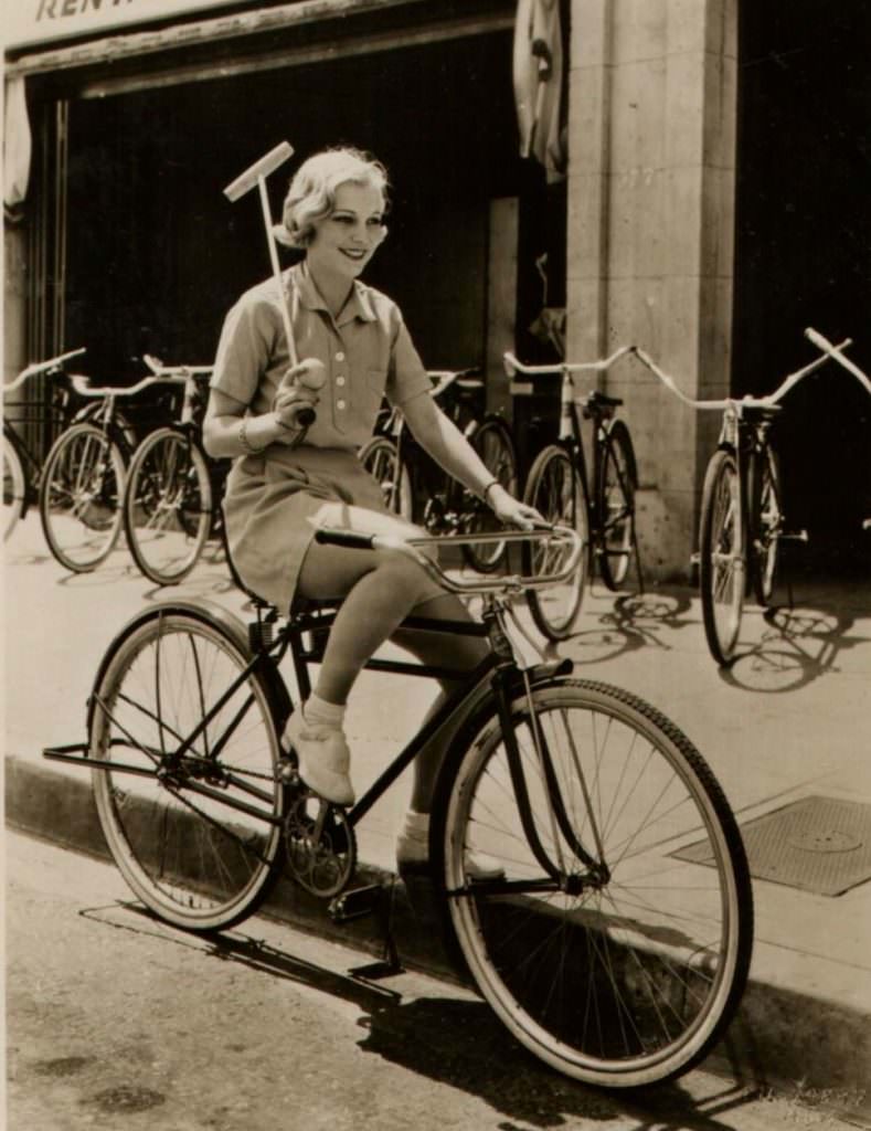 #56 Muriel Evans riding a bike, wields a mallet.