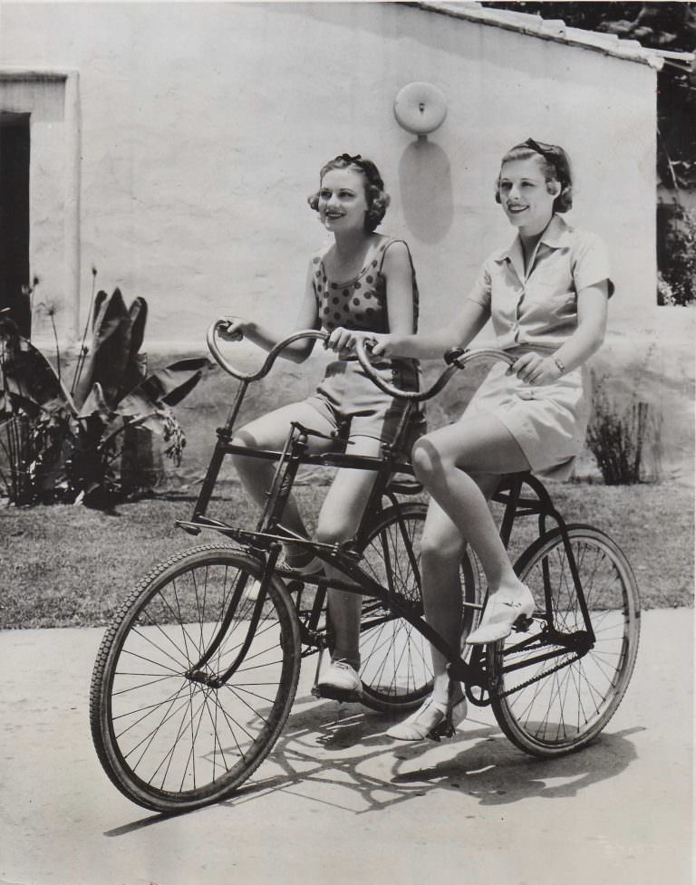 #11 Jean Howard and Irene Hervey ride a buddy bike.