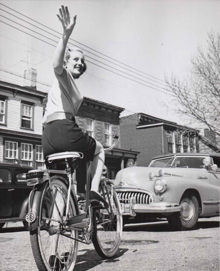 #12 Jan Sterling riding bike, waves goodbye.