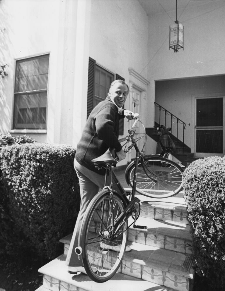 #26 McLean Stevenson carries a bike.