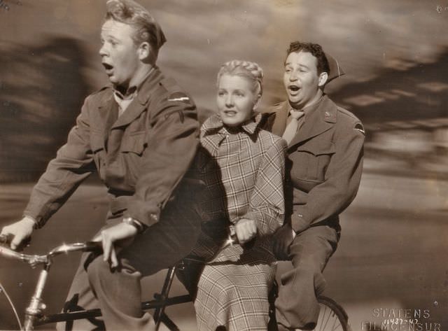 #54 Bill Murphy, Jean Arthur and Stanley Prager riding a bike.
