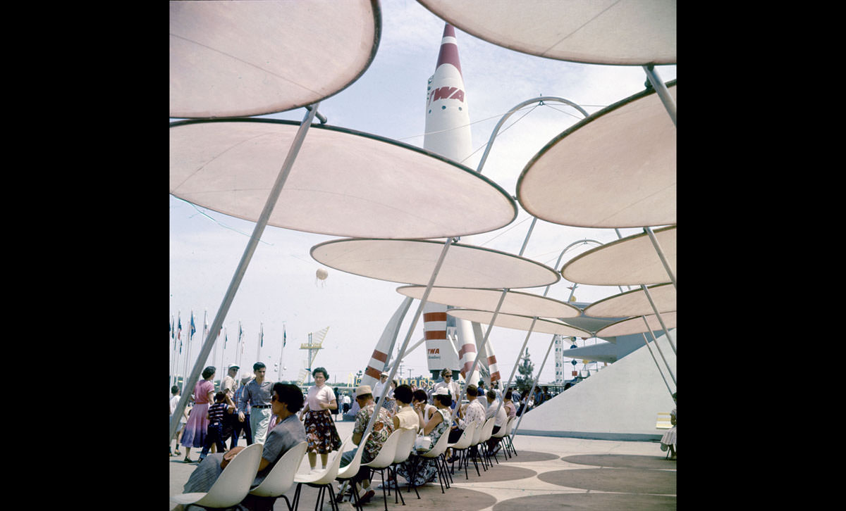 #22 Park attendees relax under sunshades near a TWA rocket in Disneyland in July 1955