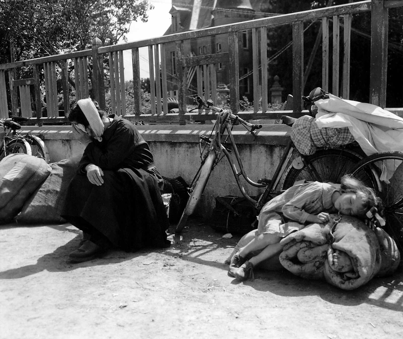 #17 On Aug. 10, 1944, a girl and her grandmother wait in a schoolyard in Saint-Pois, Normandy, France. Refugees fled to Saint-Pois to escape the fighting in Mortaine during the final battle for Normandy.