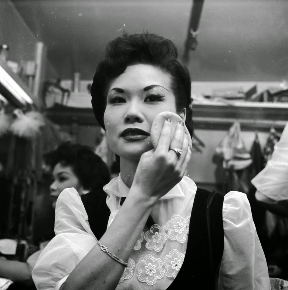 #19 A chorus girl at the Forbidden City nightclub adds the finishing touches to her makeup.