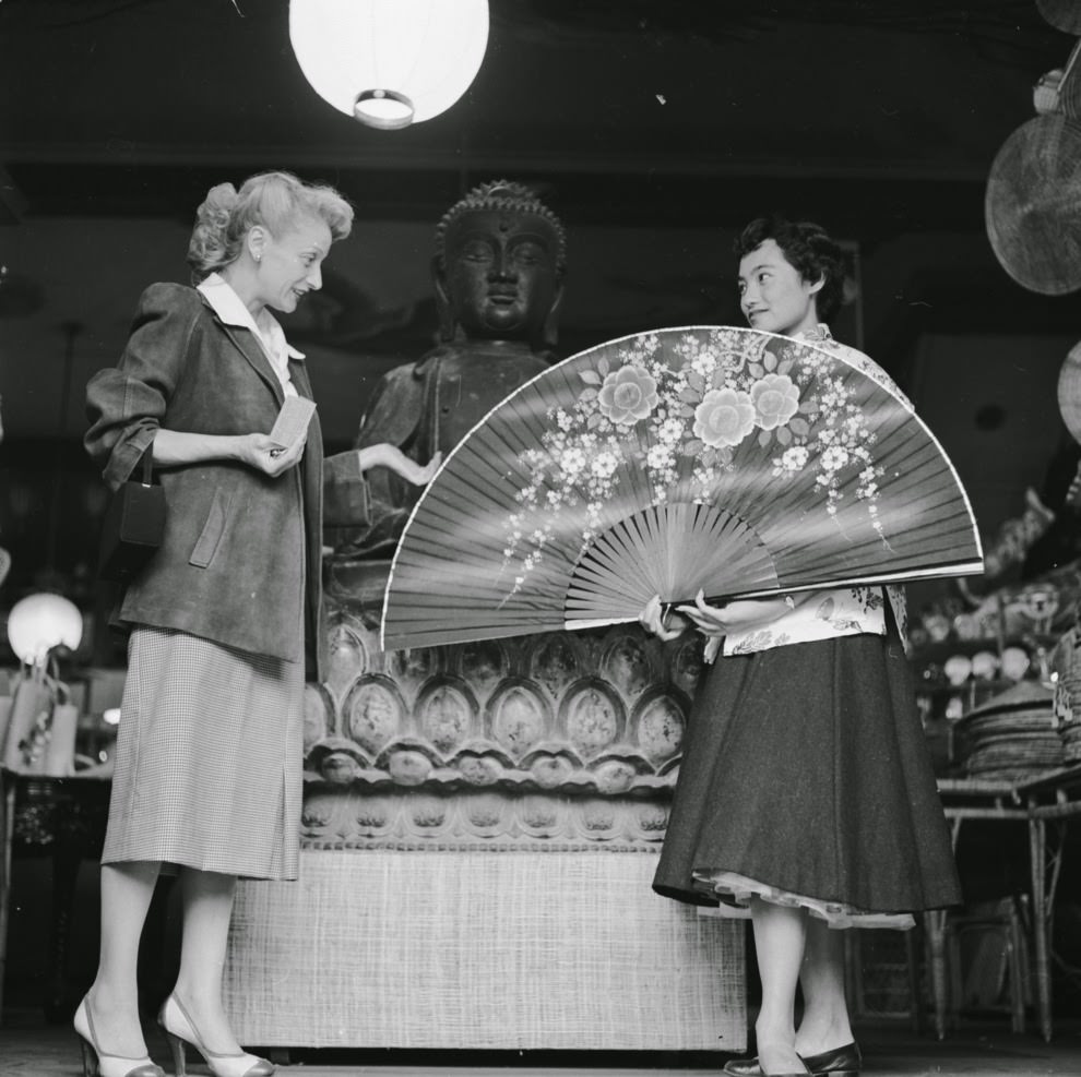 #42 A shop assistant at the Tai Ping Company boutique on Grant Avenue demonstrates a giant Chinese fan to an interested customer.