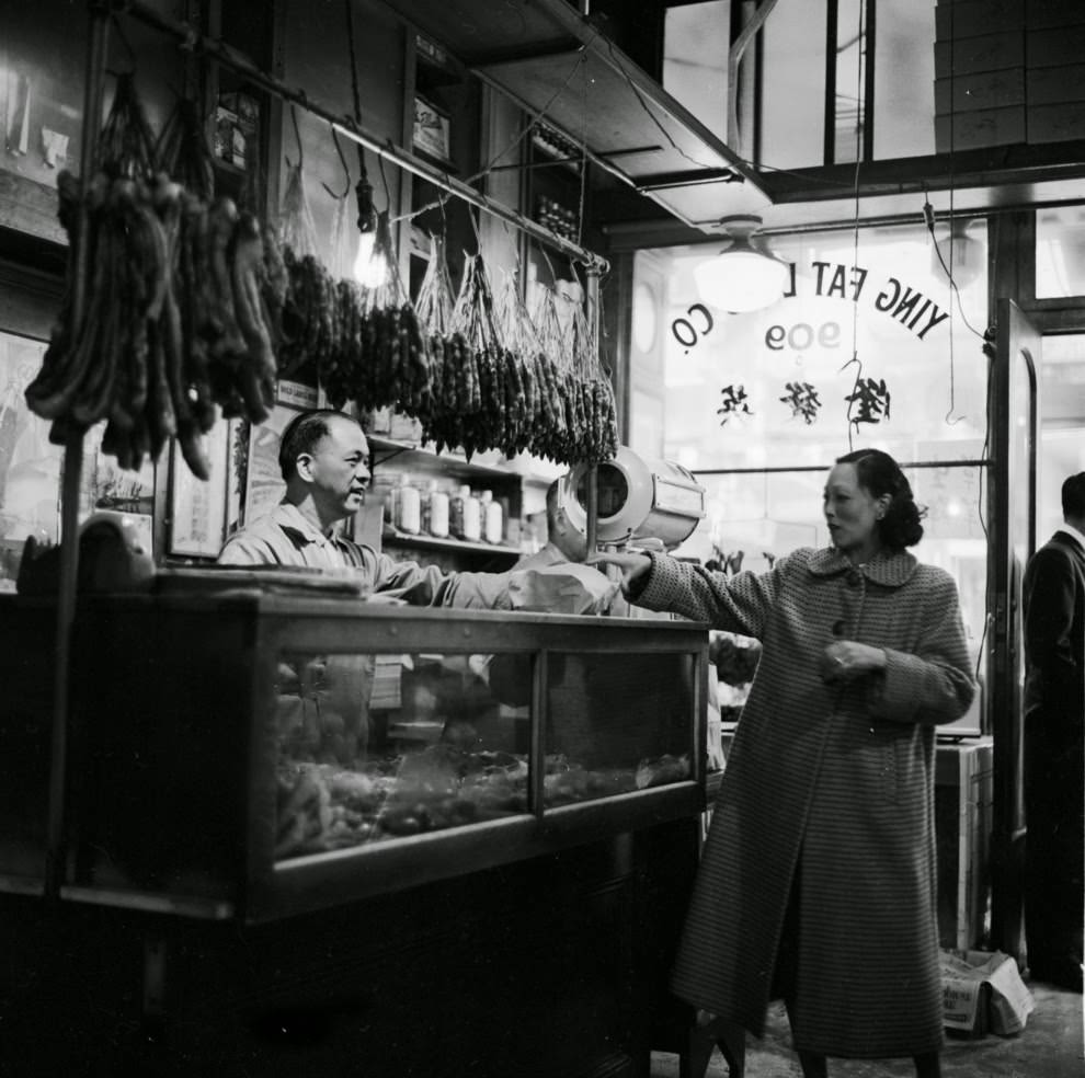 #32 A customer receives her order from the butcher at Ying Fat Lung’s Chinese shop.